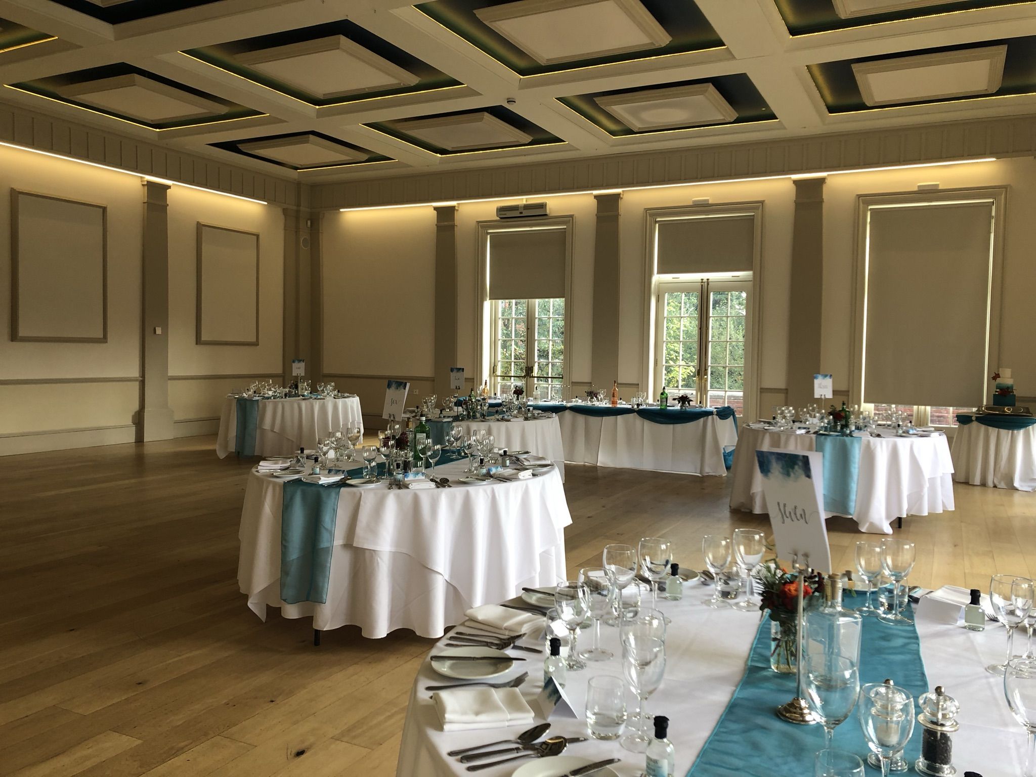a banquet hall with tables and chairs covered in blue and white linens.