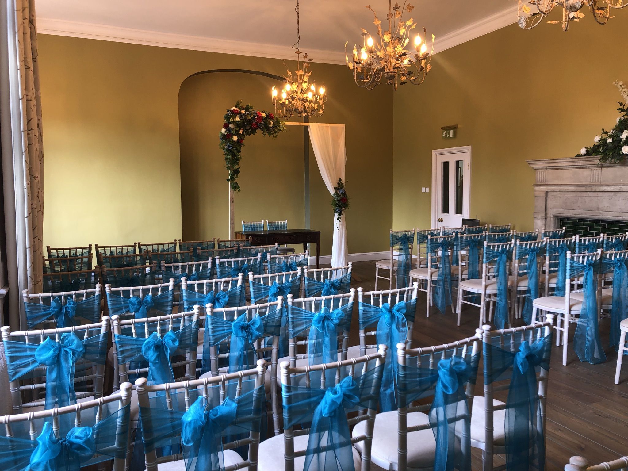 a room filled with lots of white chairs covered in blue bows.