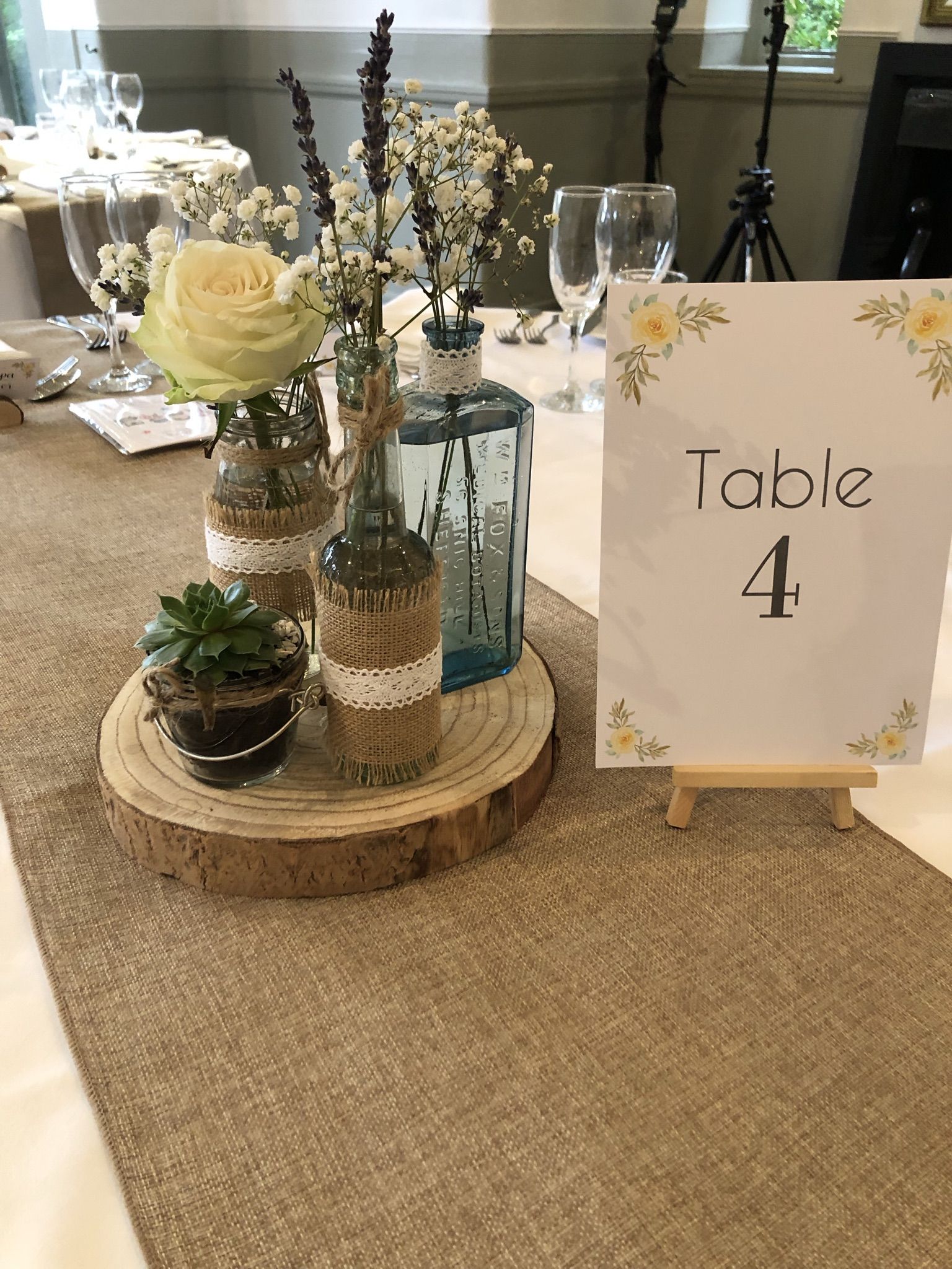 a table with a sign and vases of flowers.