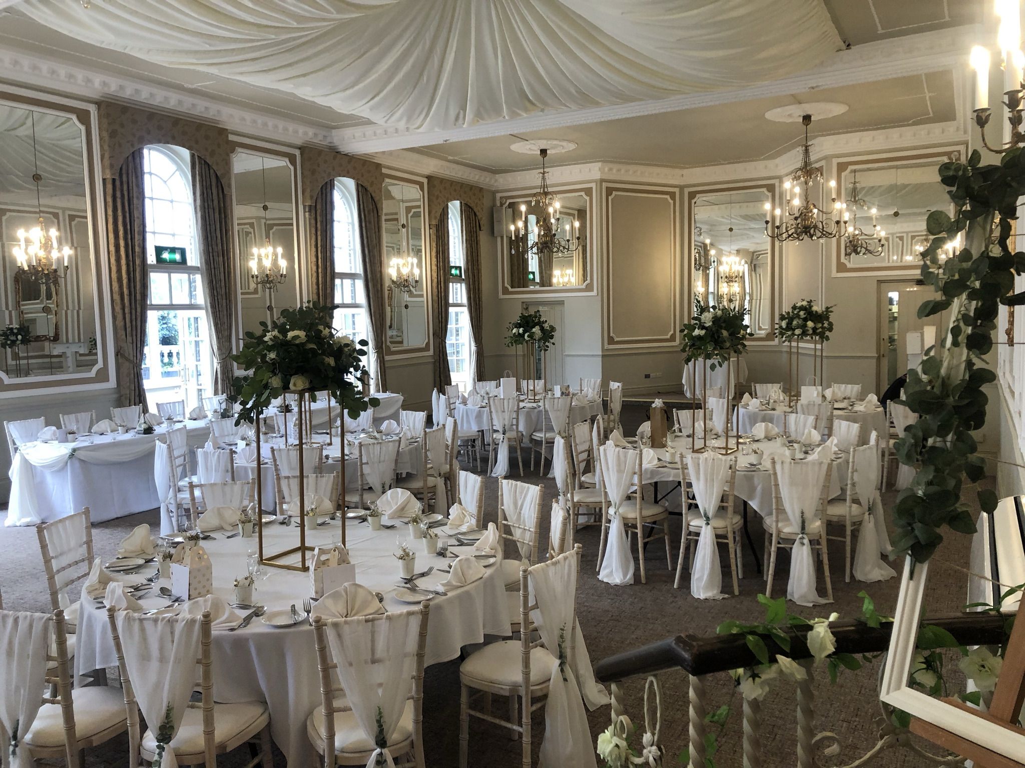 a room filled with tables and chairs covered in white linens.