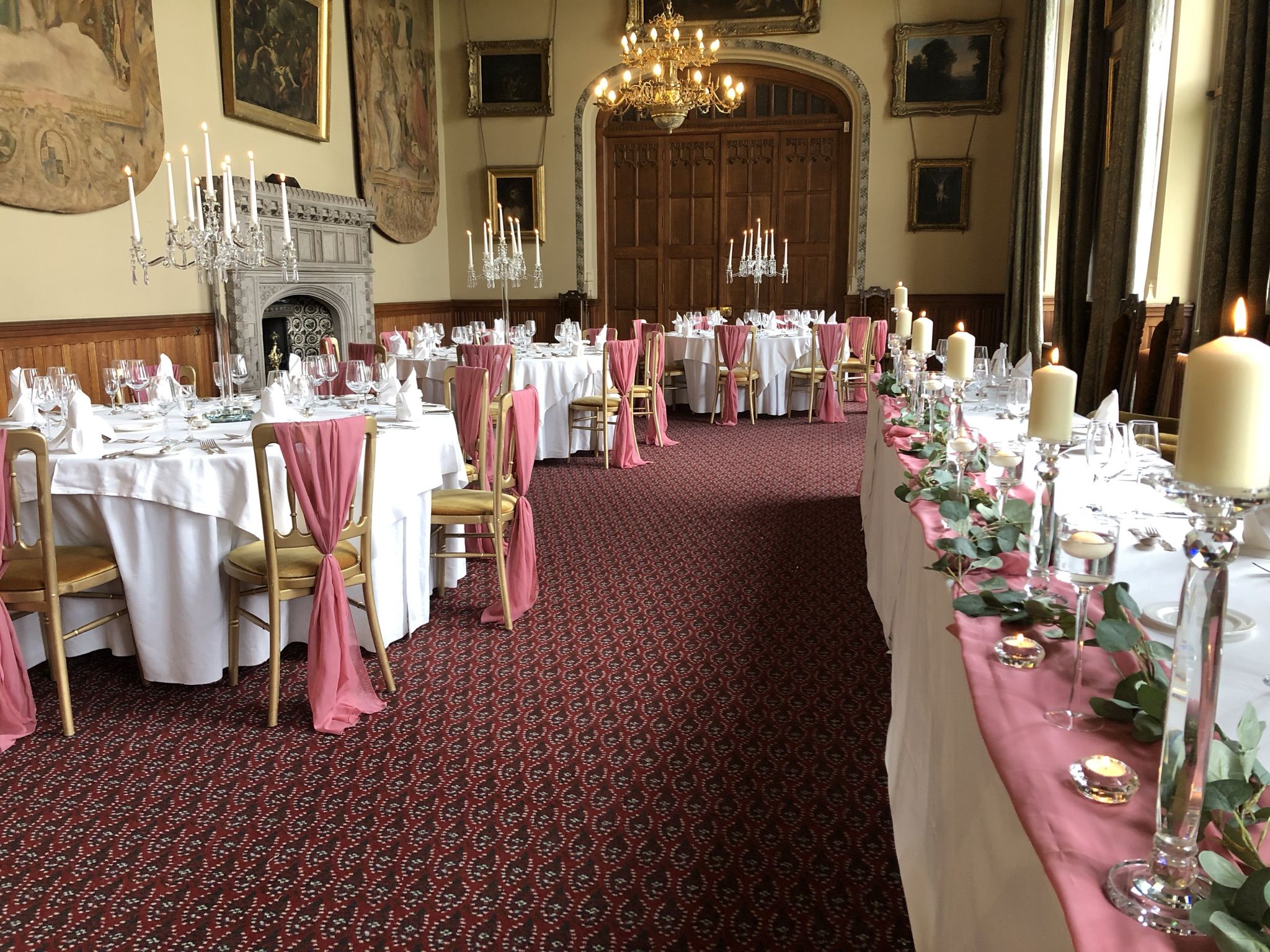 a banquet hall with tables and chairs covered in pink and white linens.