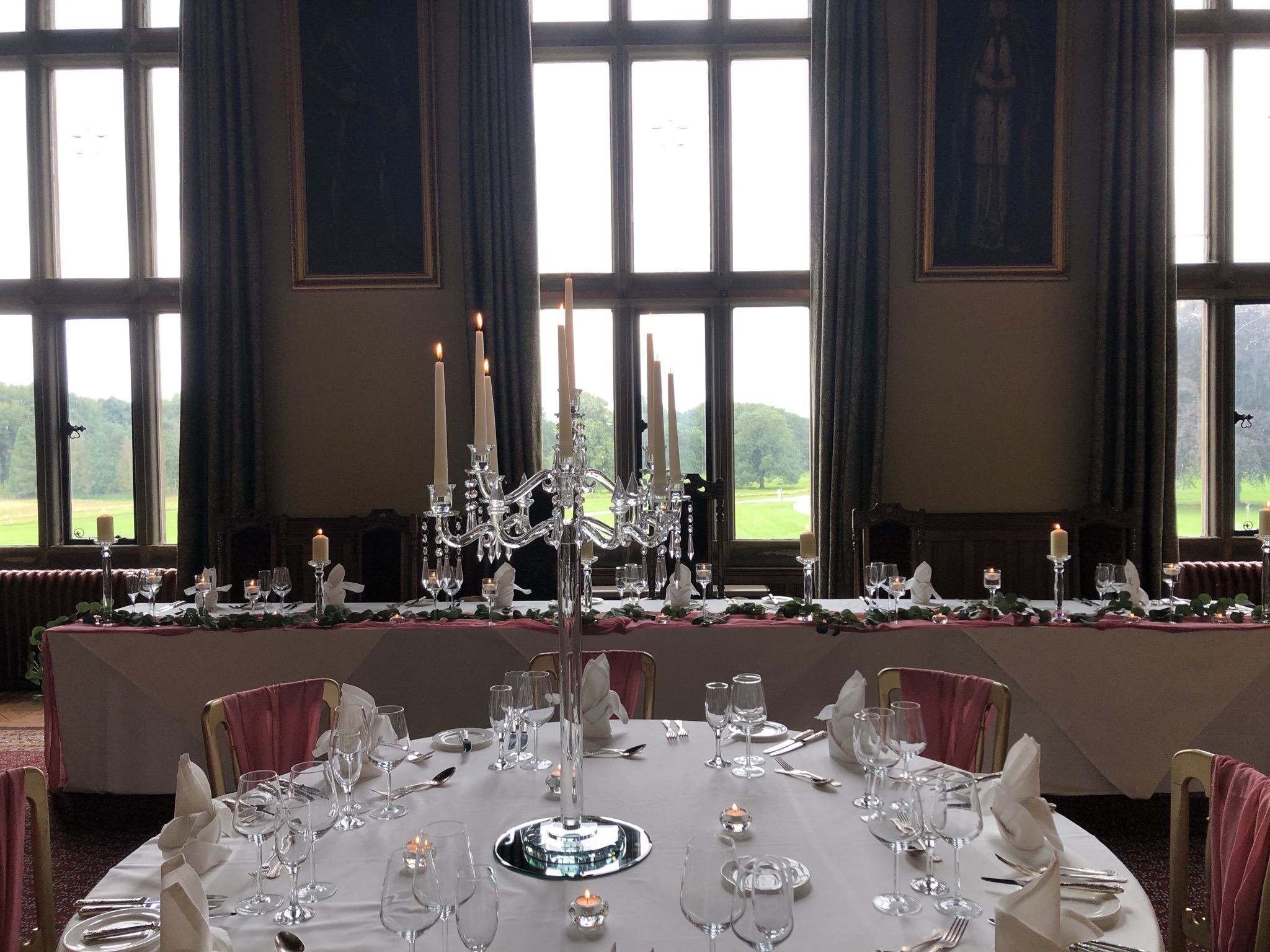 a table set for a formal dinner in front of large windows.
