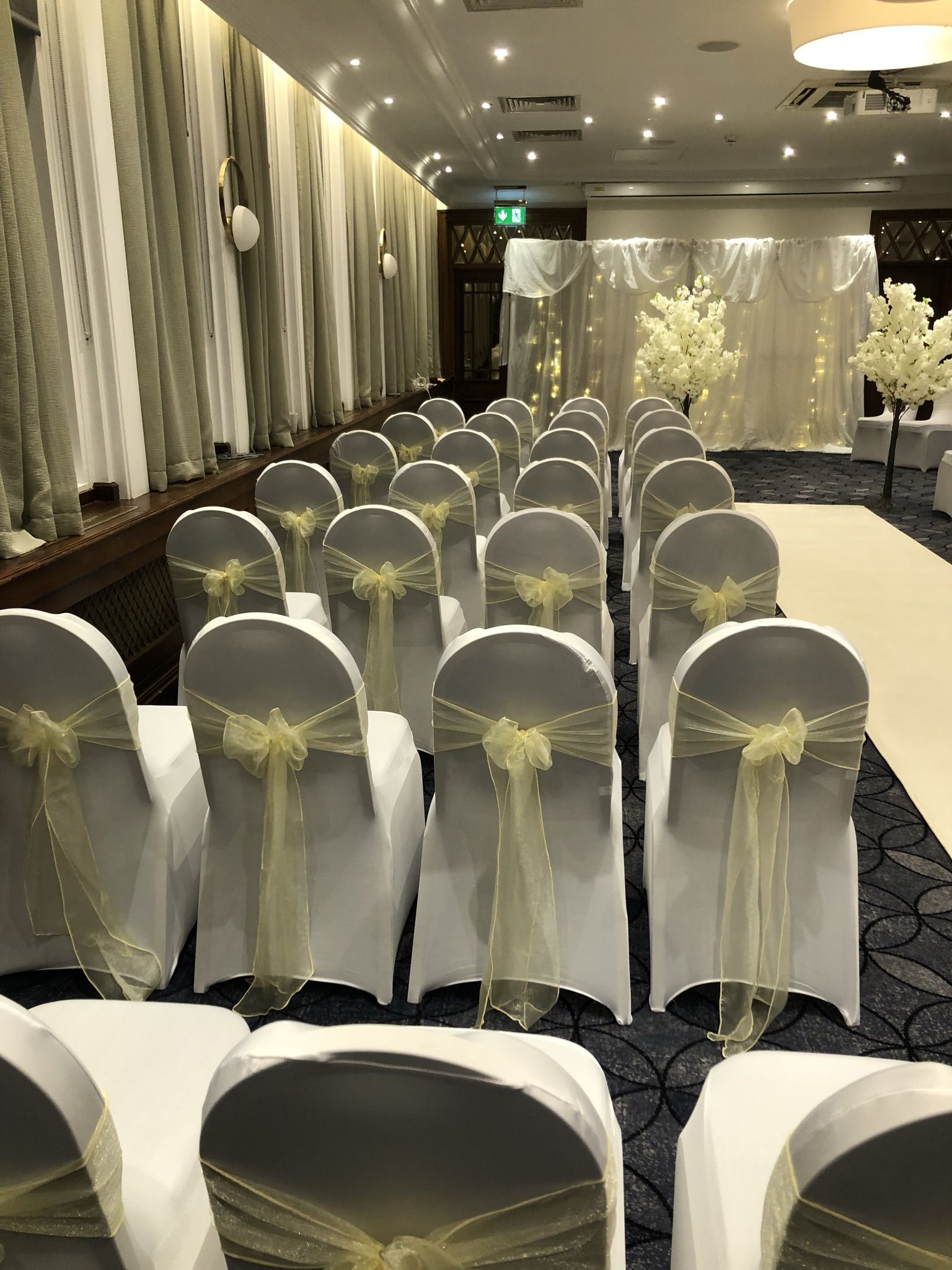 rows of white chairs with yellow sashes and bows.