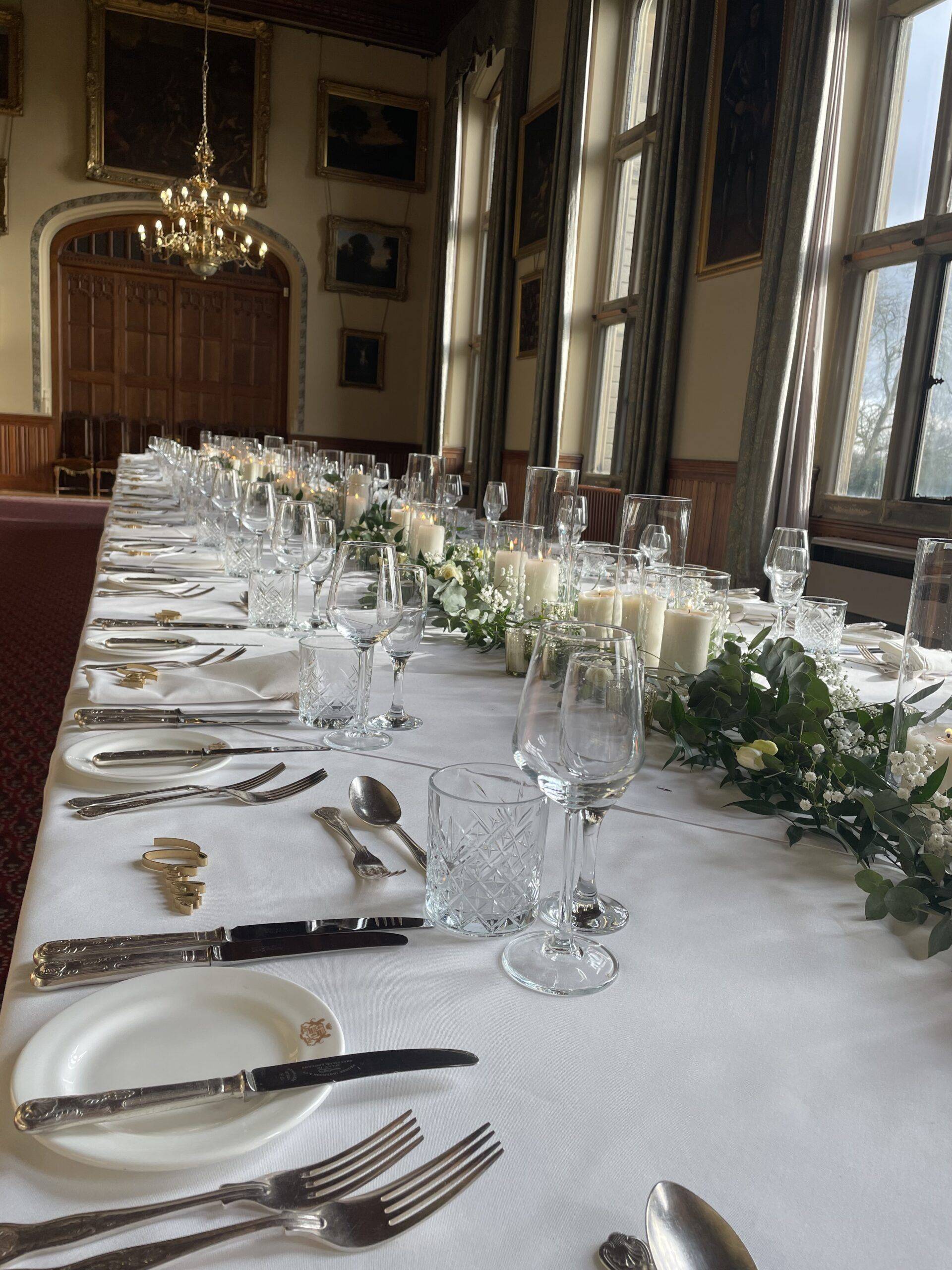 a long table is set with silverware and candles.