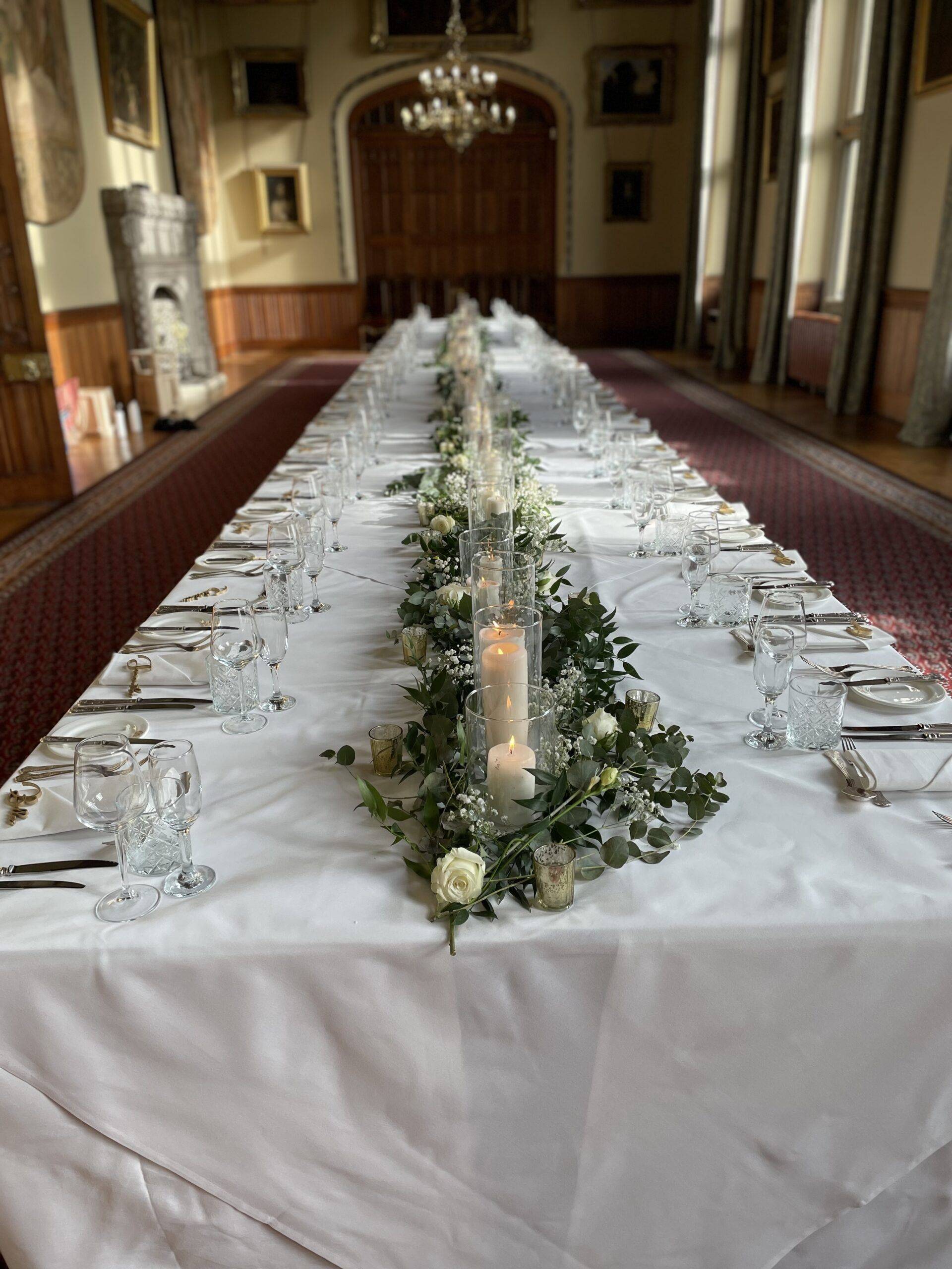 a long table with a candle and flowers on it.