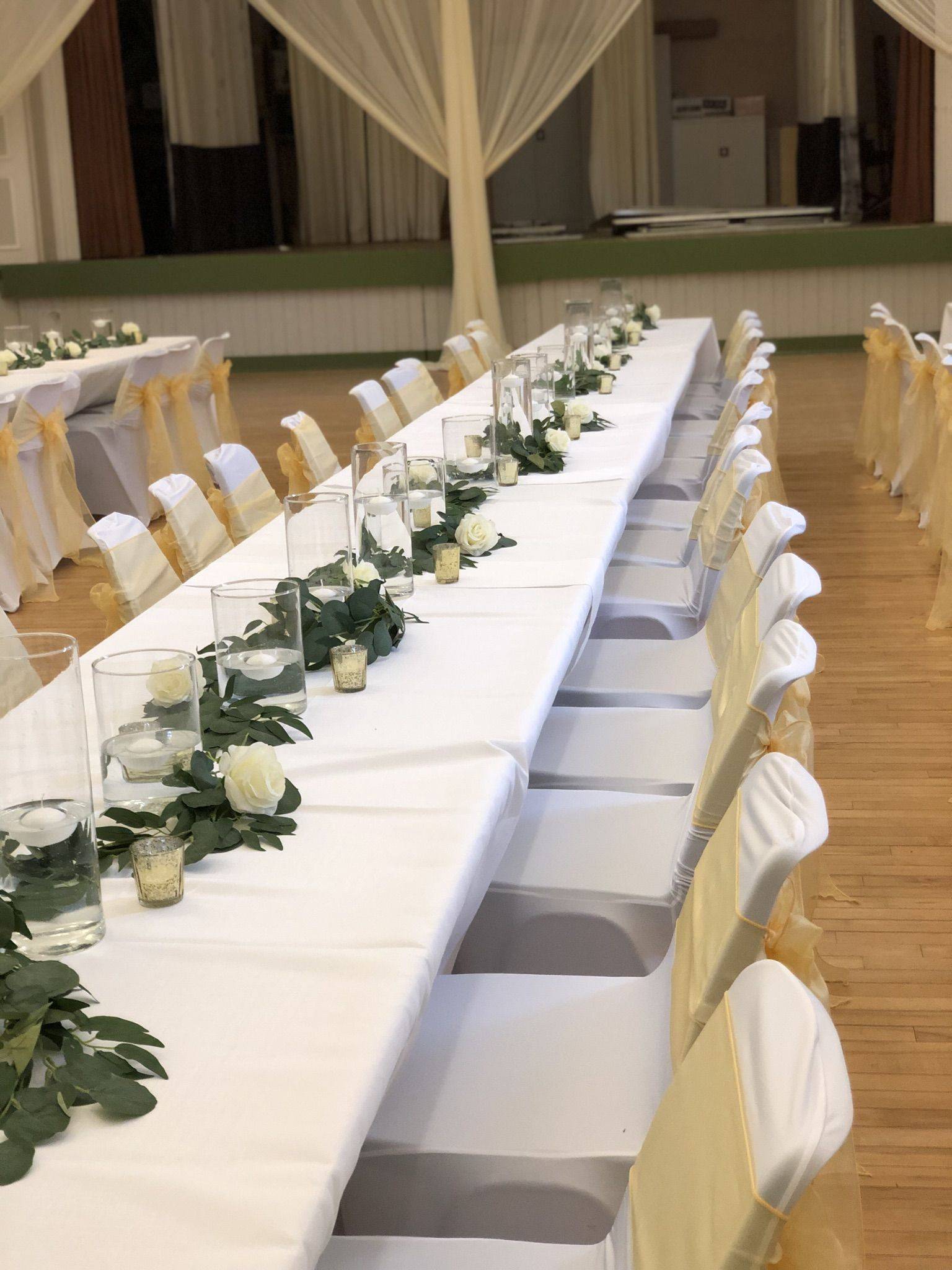 a long table with white linens and flowers on it.