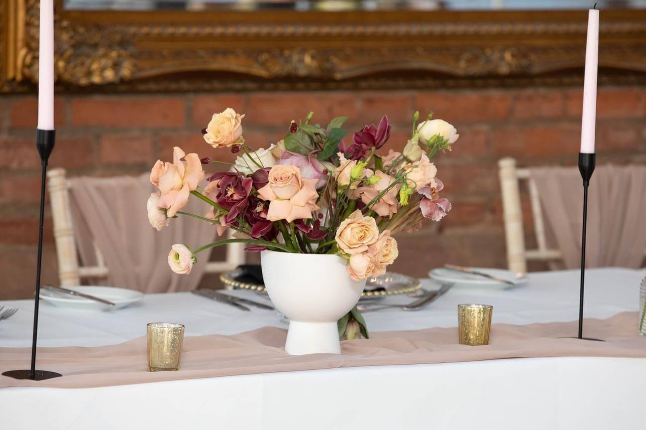 a vase of flowers on a table with candles.