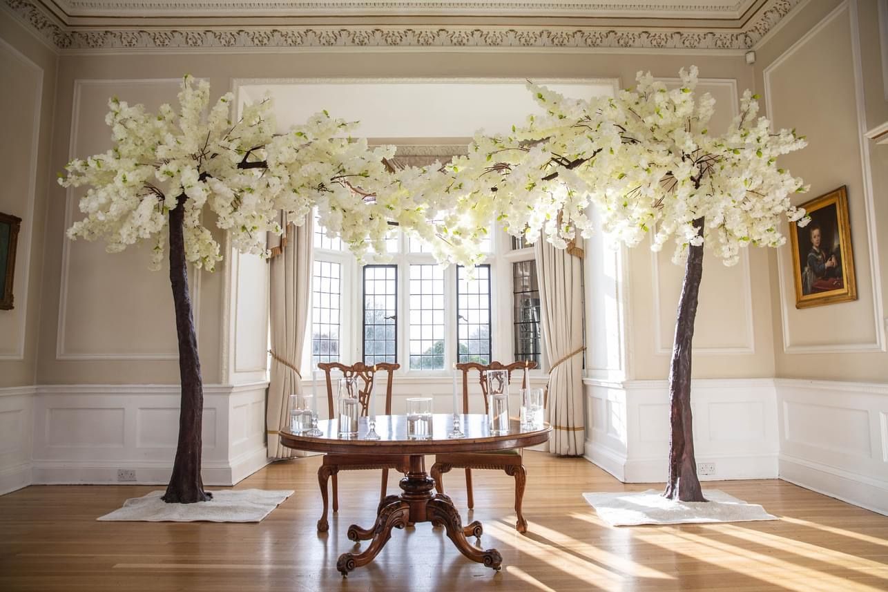 a room with a table, chairs, and two trees.
