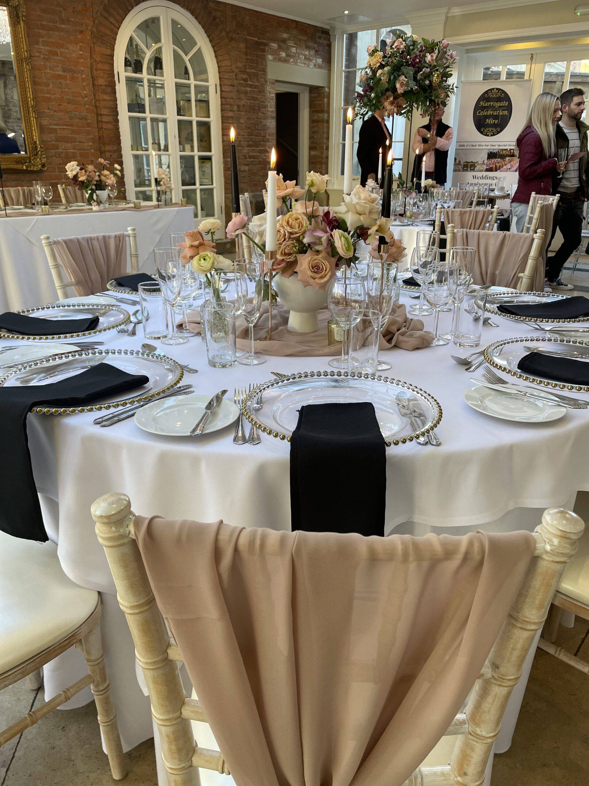 a table set for a formal dinner with black and white linens.