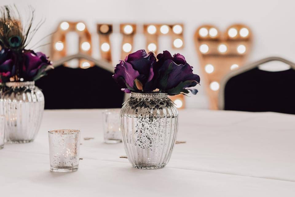 a white table topped with vases filled with purple flowers.