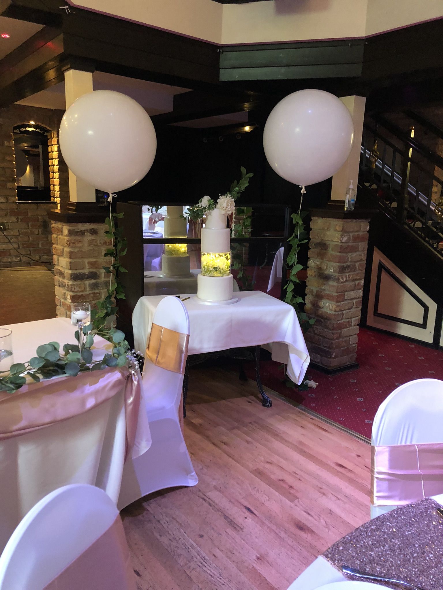 a table with a cake and balloons in a room.