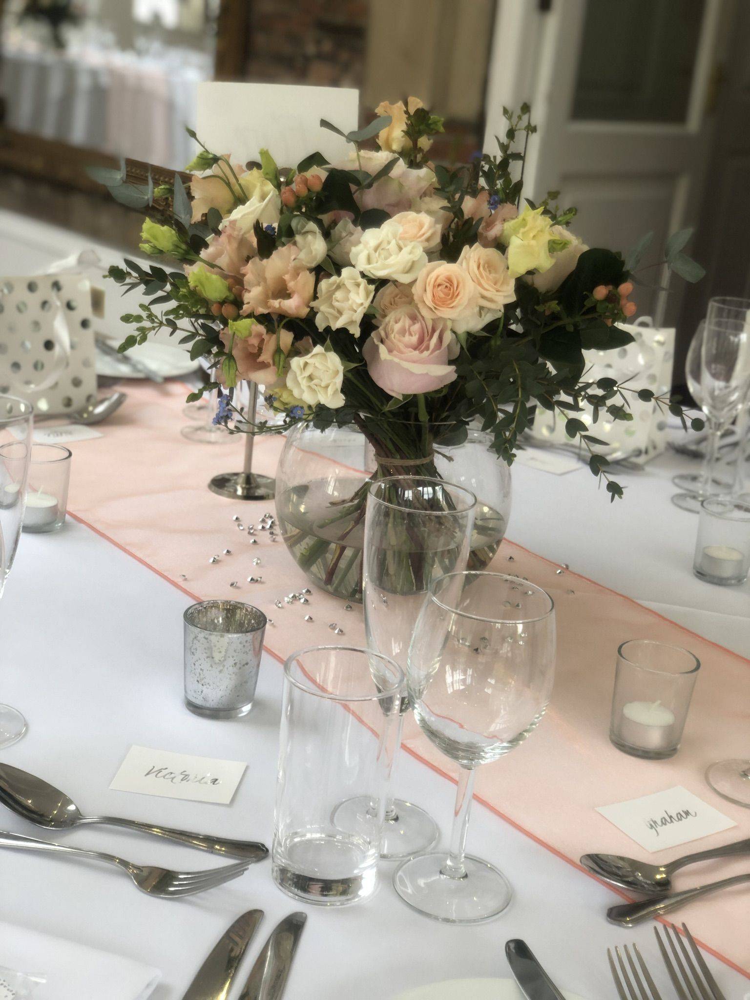 a table with a vase of flowers and silverware.