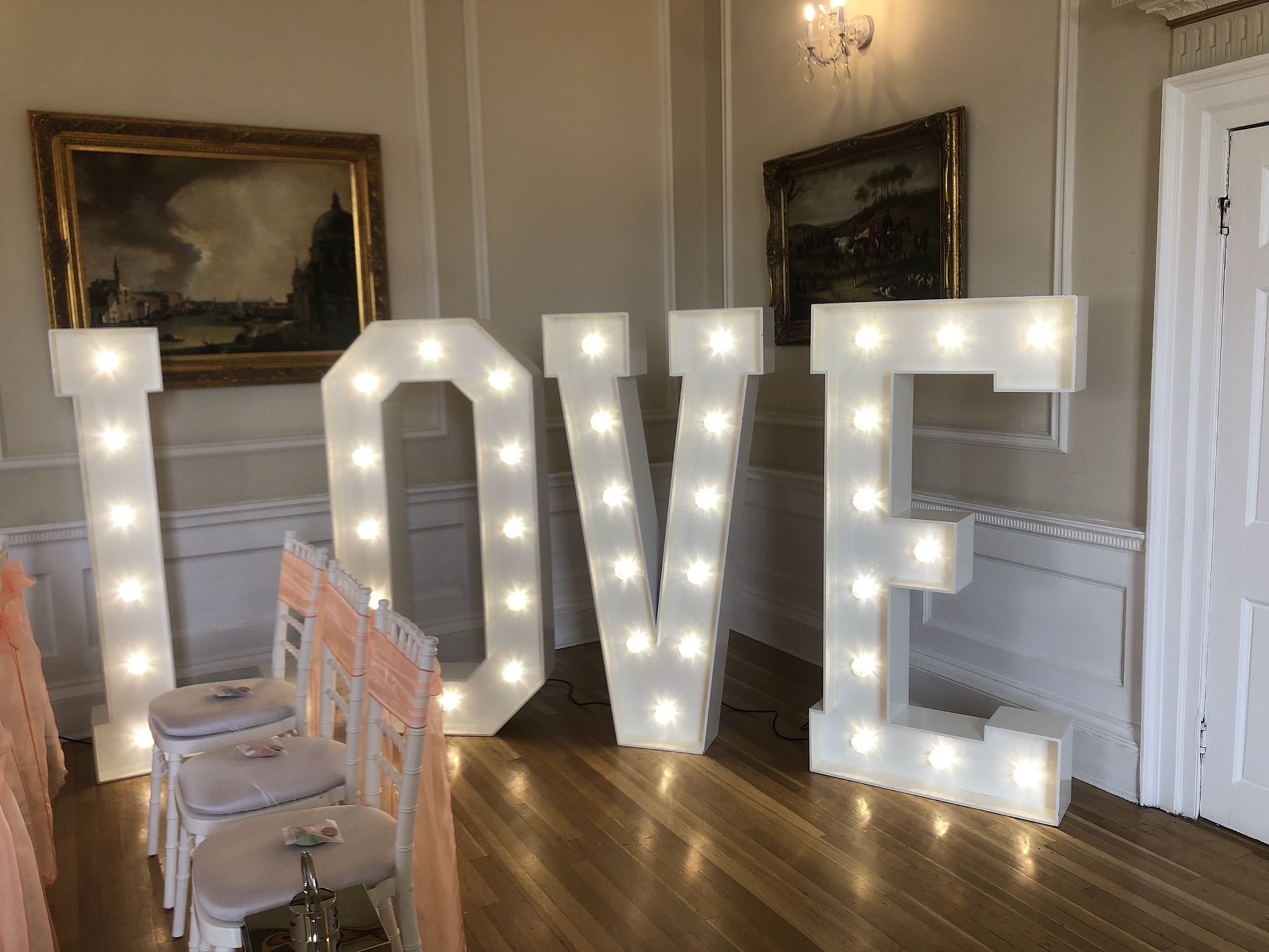 a large lighted love sign sitting on top of a hard wood floor.