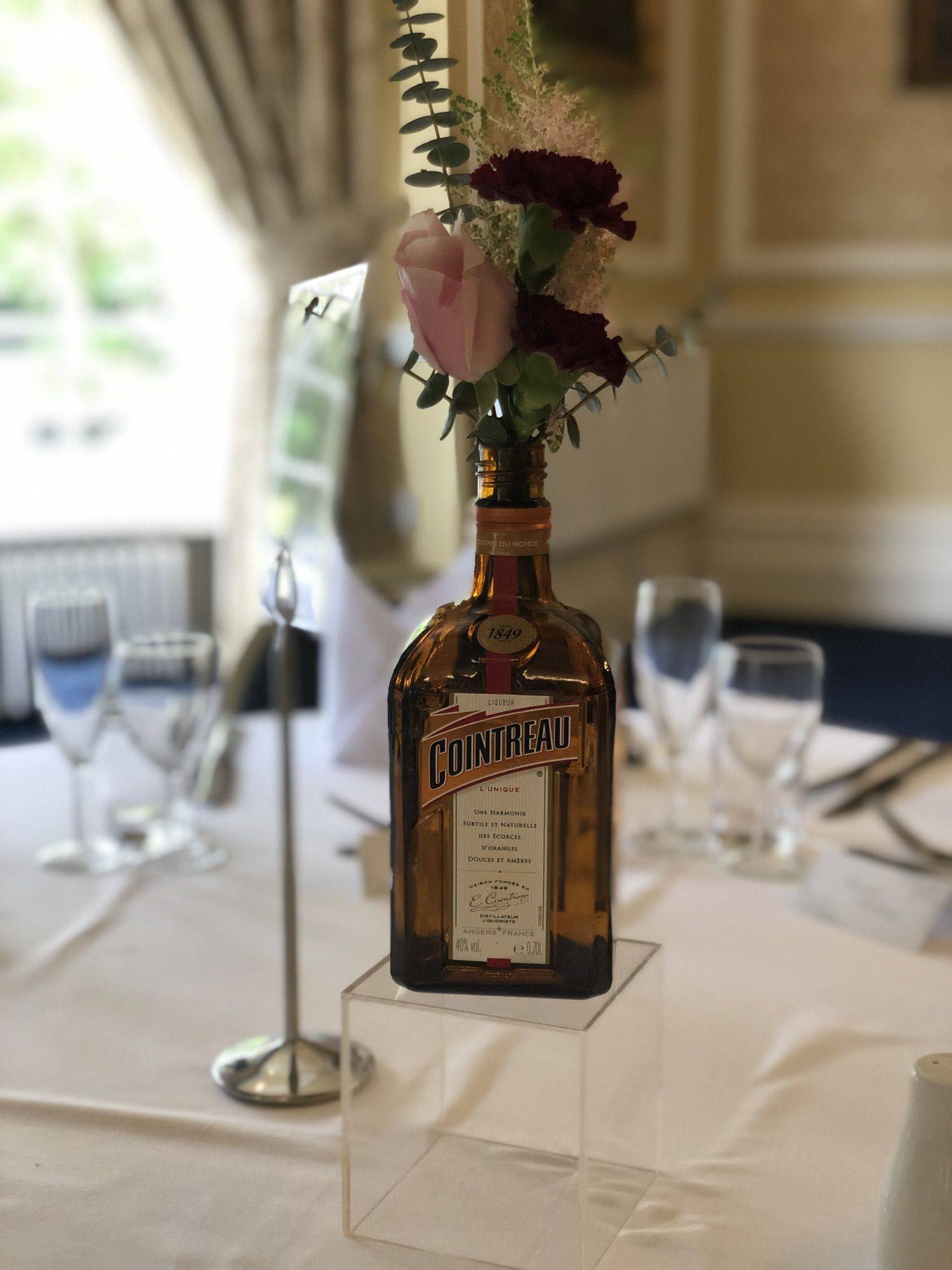 a bottle with flowers in it sitting on a table.