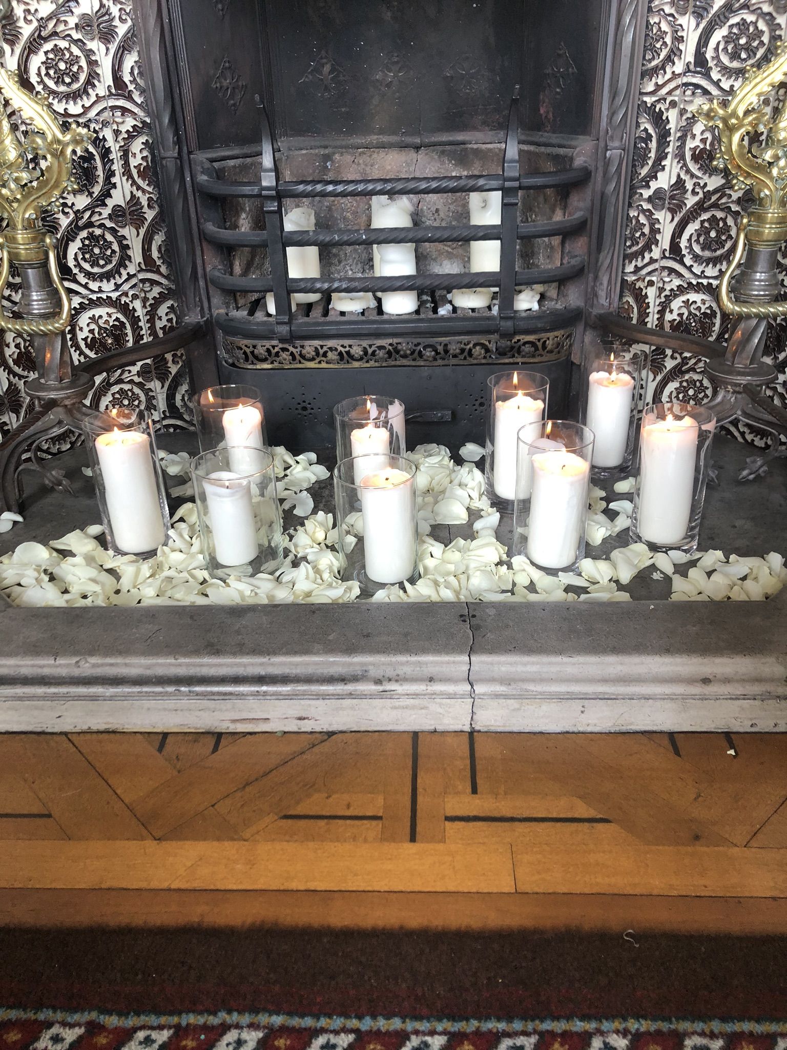 a fireplace with candles and flowers on the mantle.