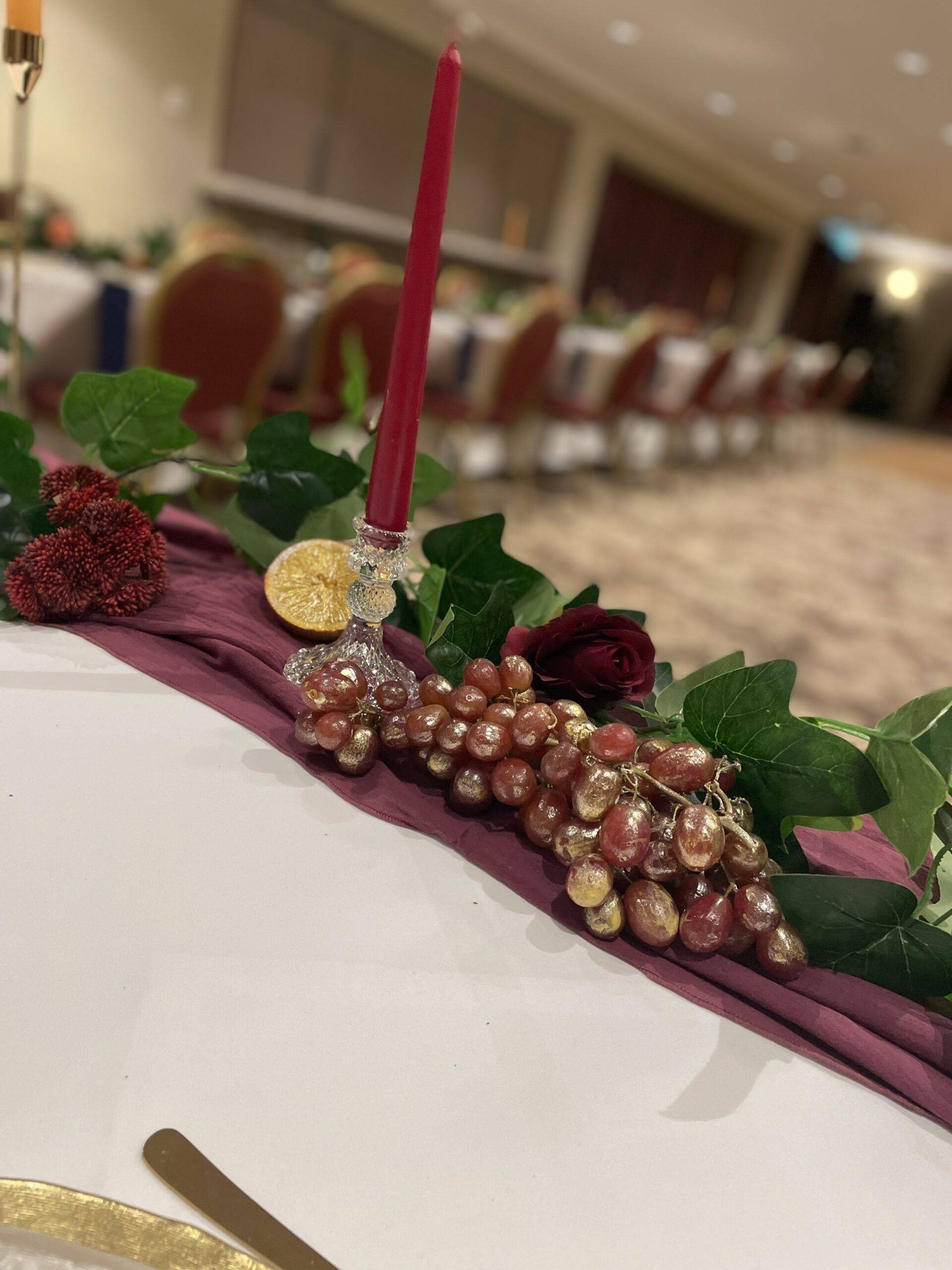 a table with a candle and a bunch of grapes on it.