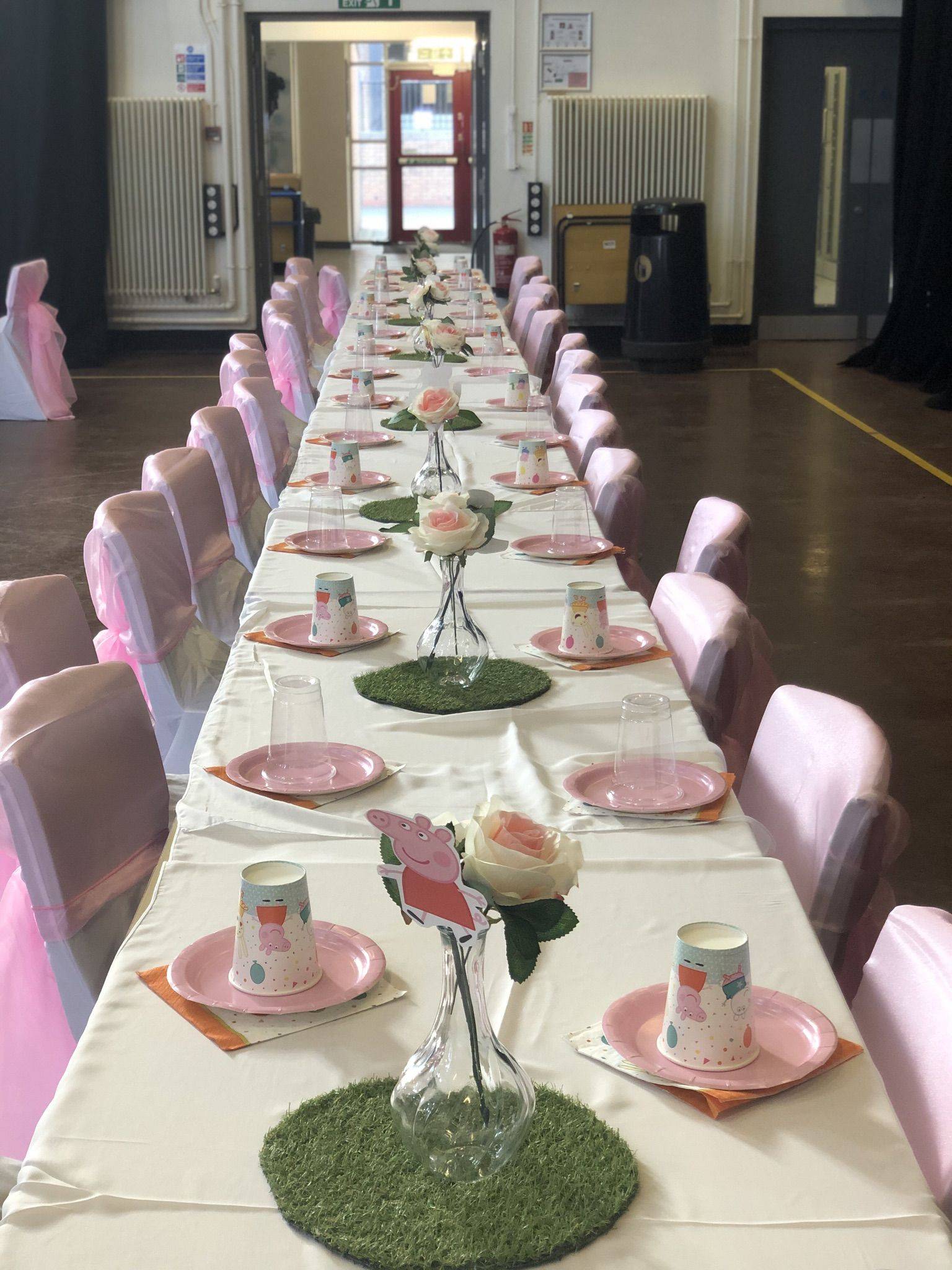 a long table with pink chairs and plates.