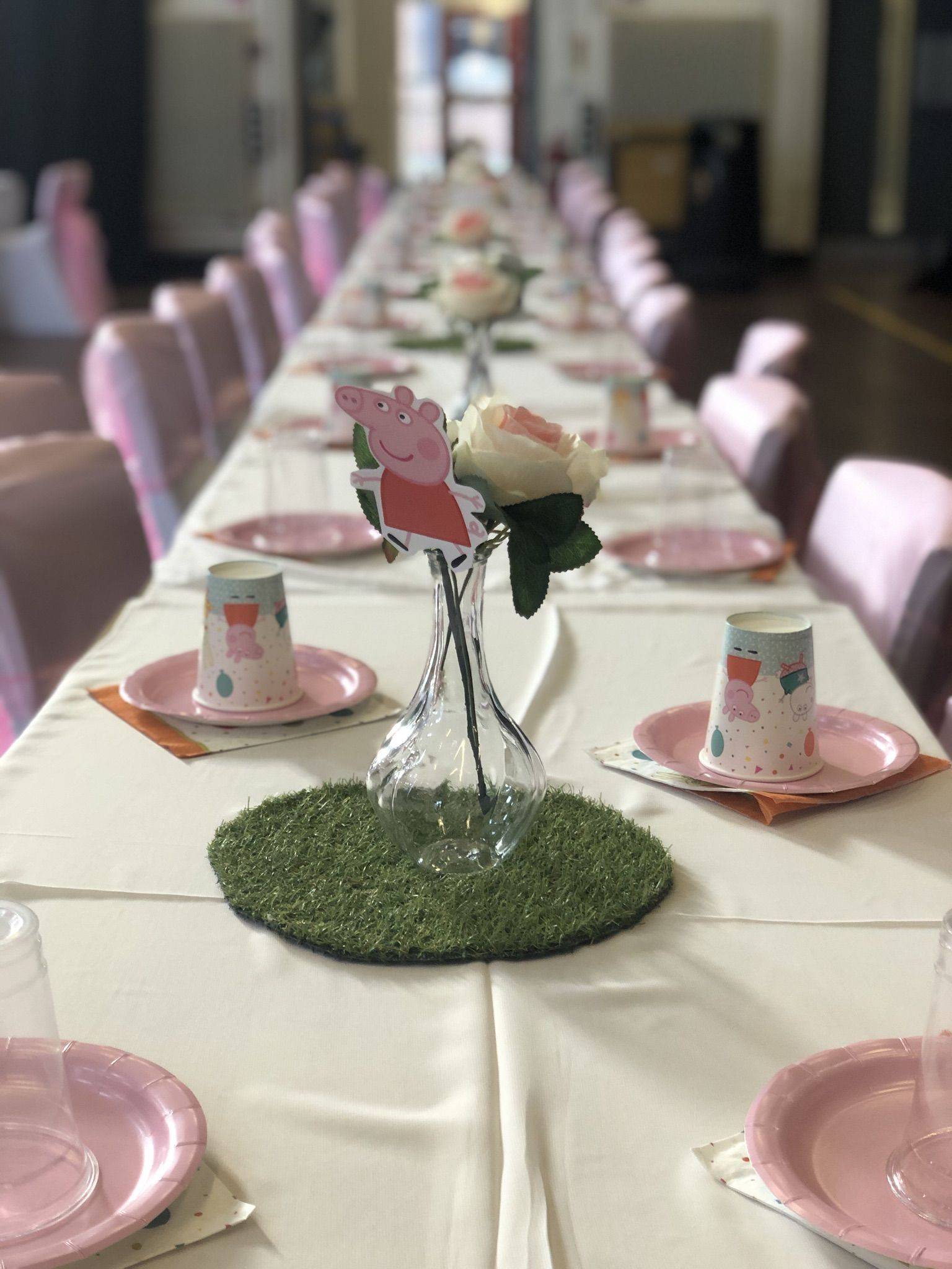 a long table is set with pink plates and pink napkins.