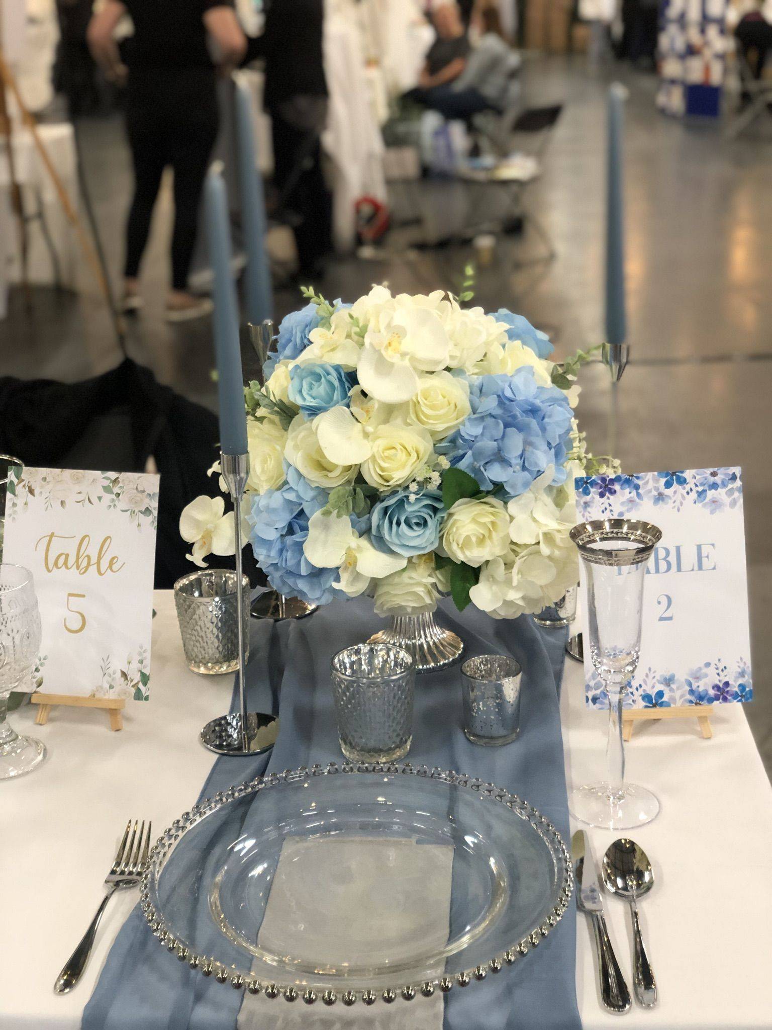 a table set for a formal dinner with blue and white flowers.