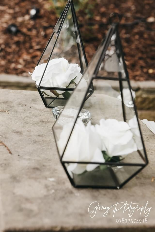 a couple of glass vases with flowers inside of them.