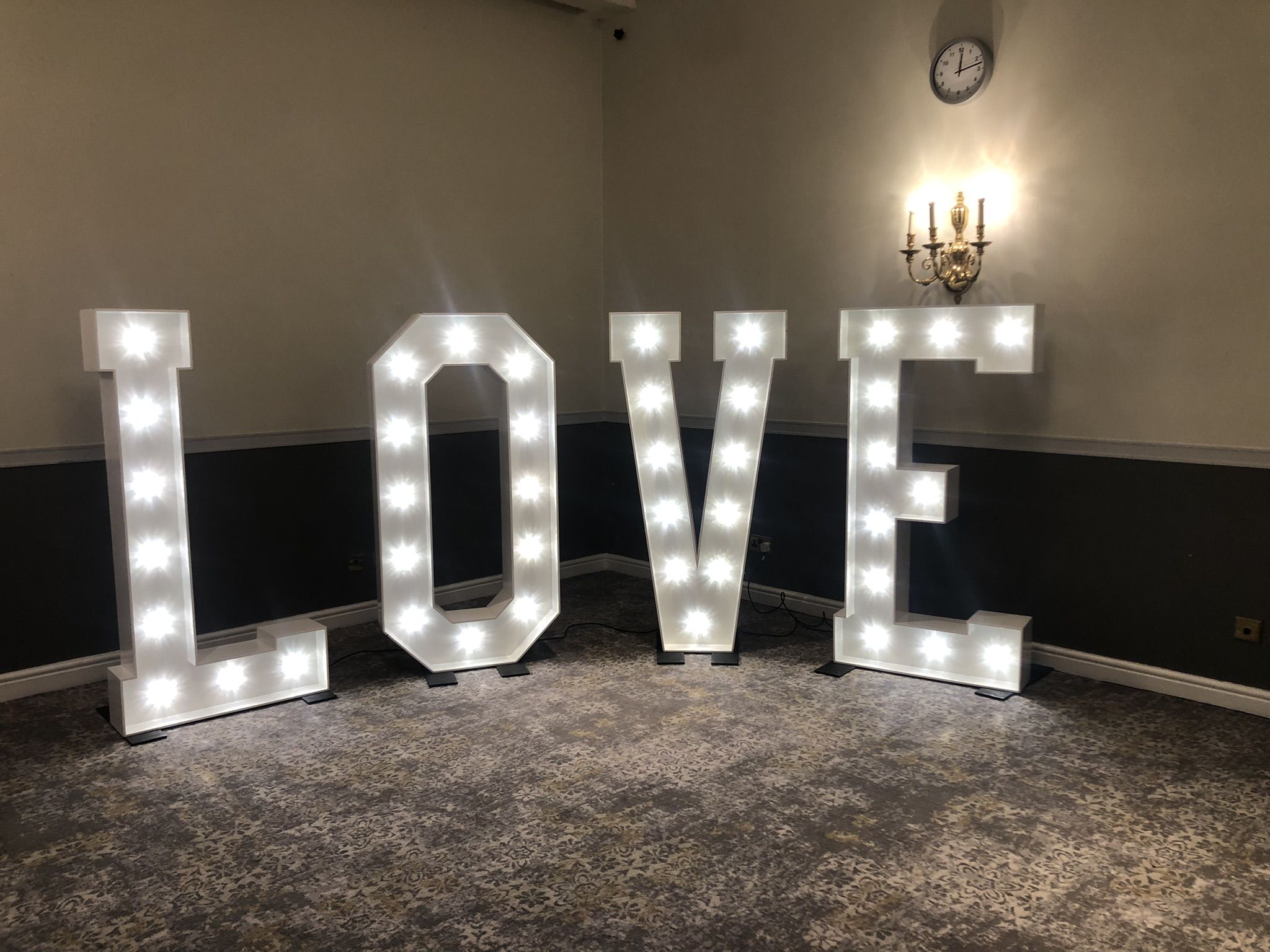a lighted love sign in a room with a chandelier.