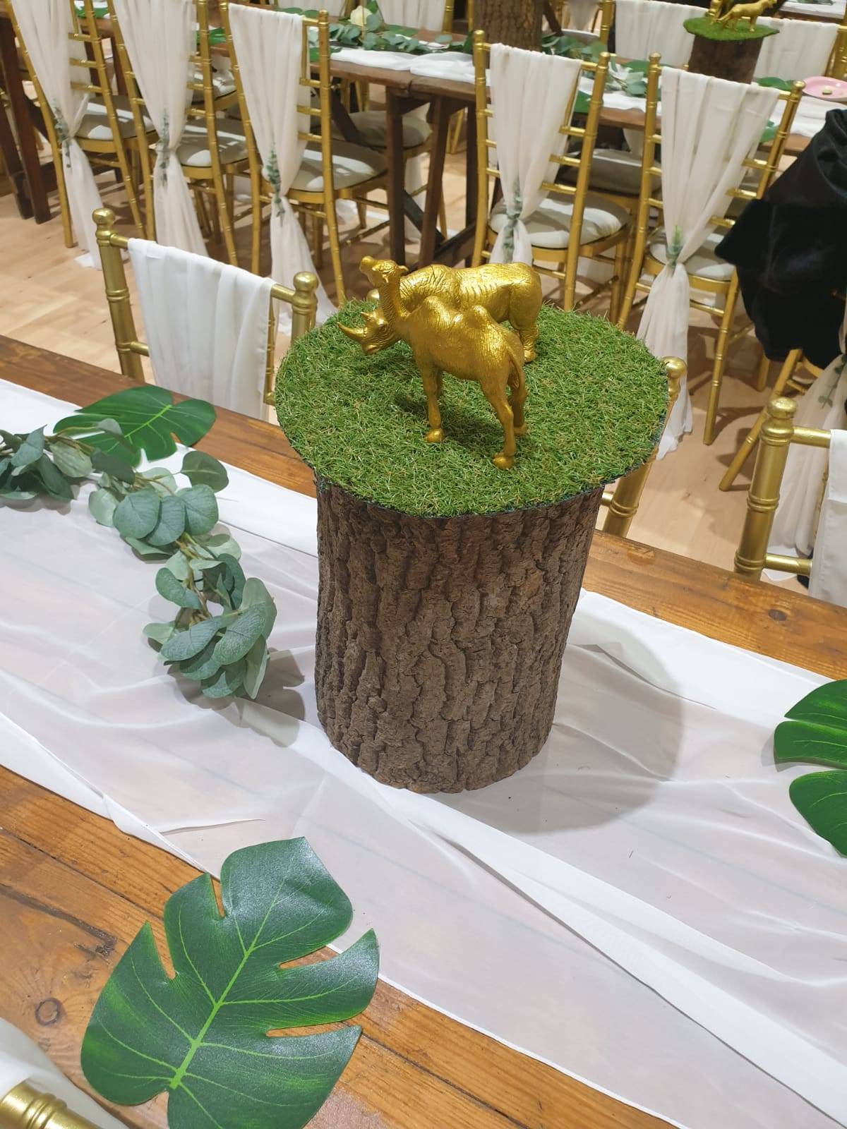 a table topped with a tree stump and a golden cow.