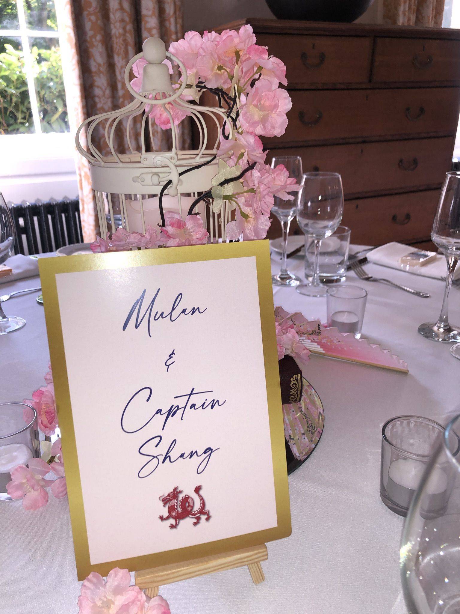 a table is set with a sign and wine glasses.