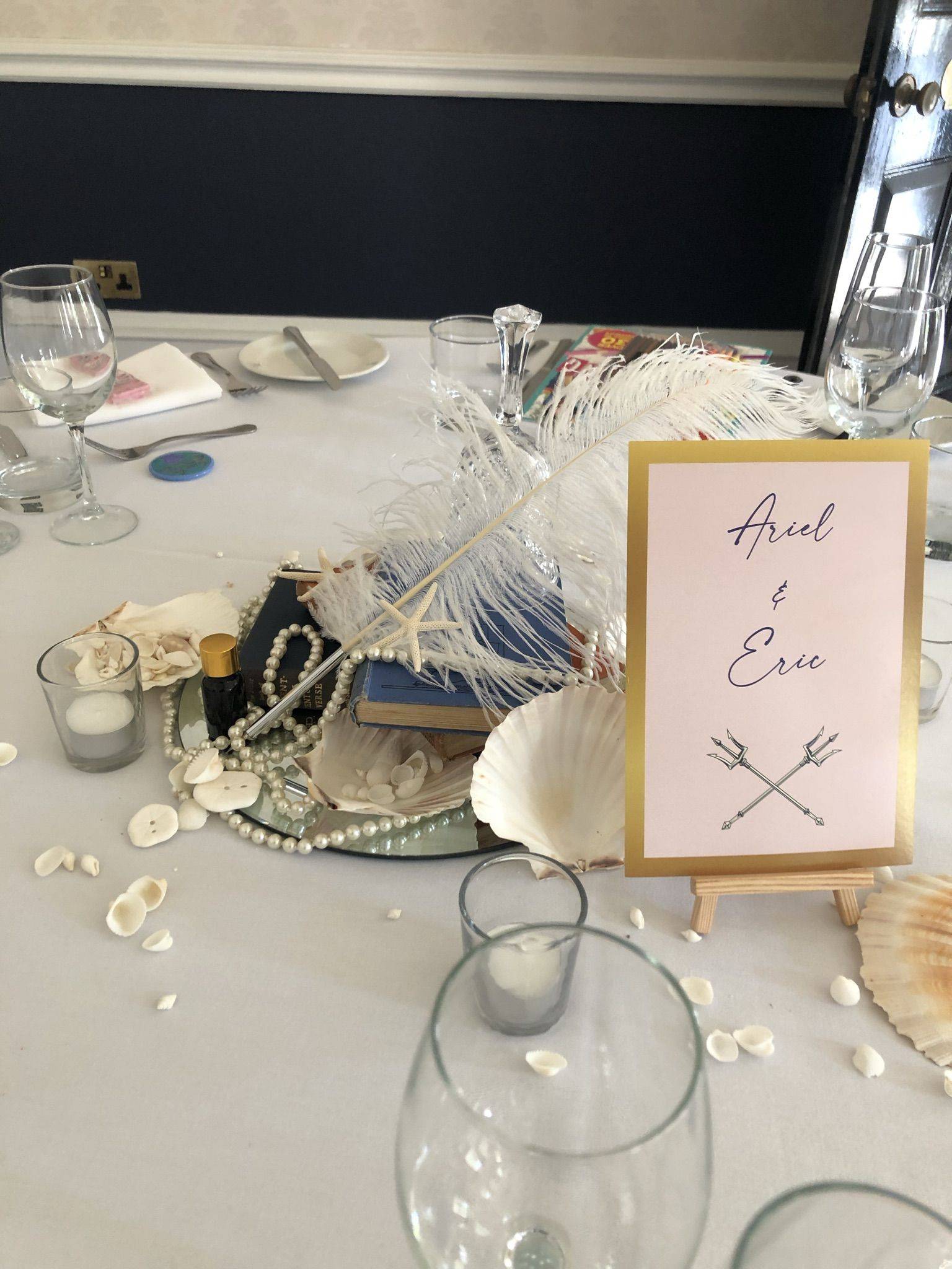 a table topped with a sign and seashells.