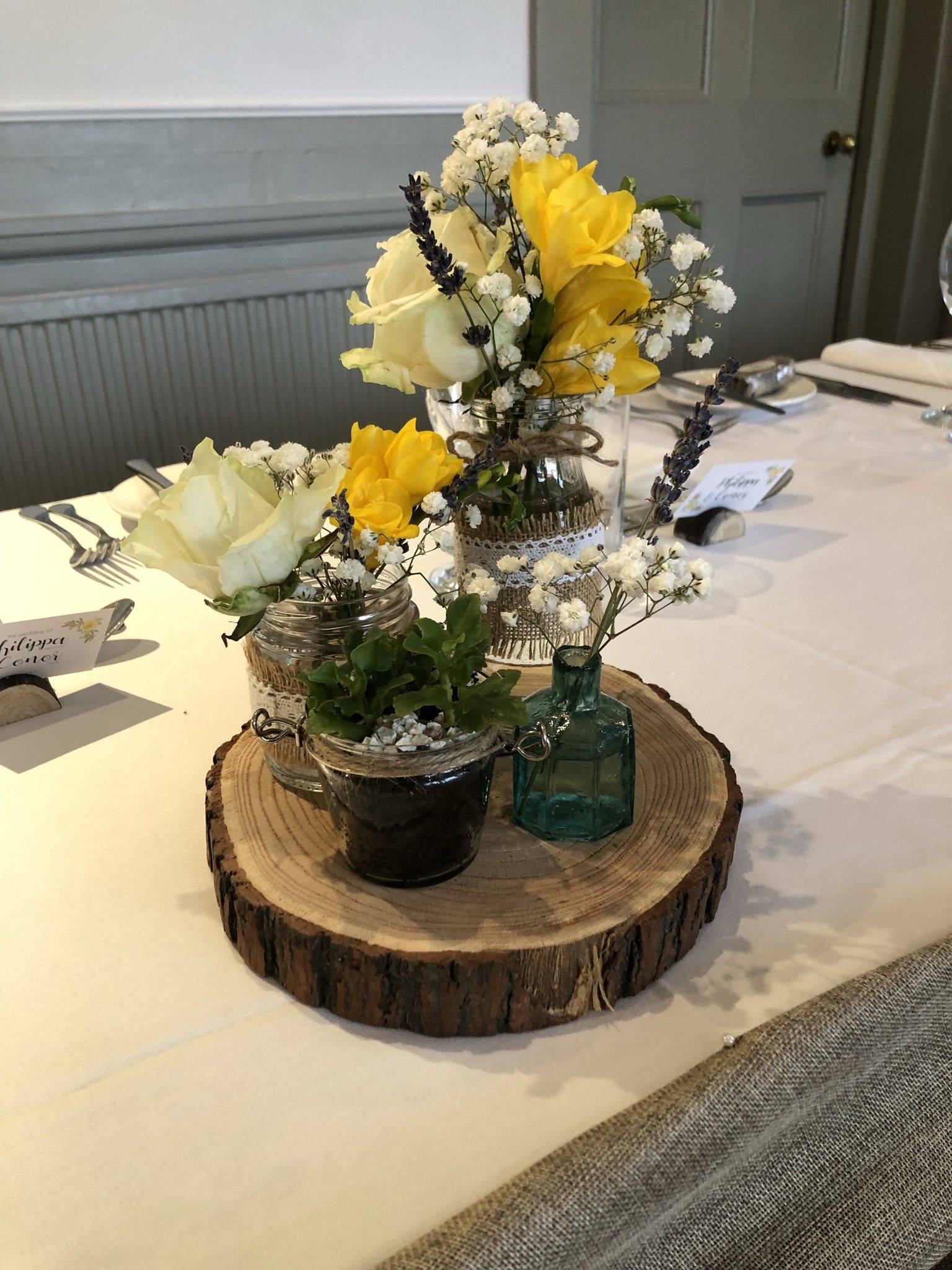 a table topped with a vase filled with yellow and white flowers.