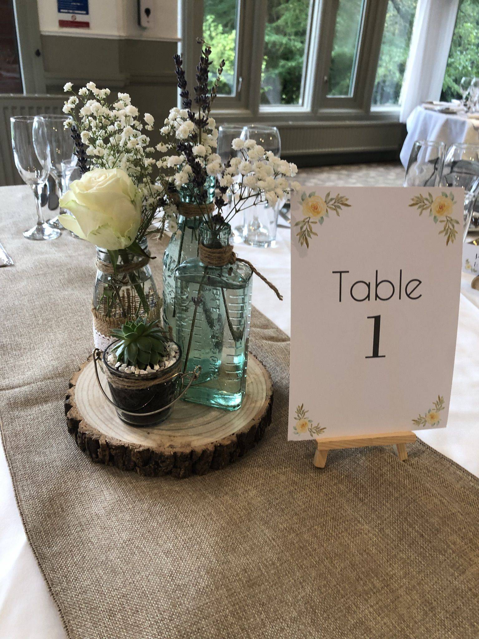 a table with a sign and vases of flowers.