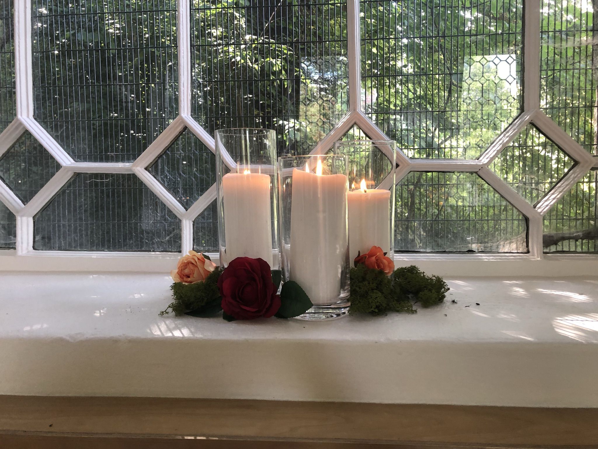 a couple of candles sitting on top of a window sill.