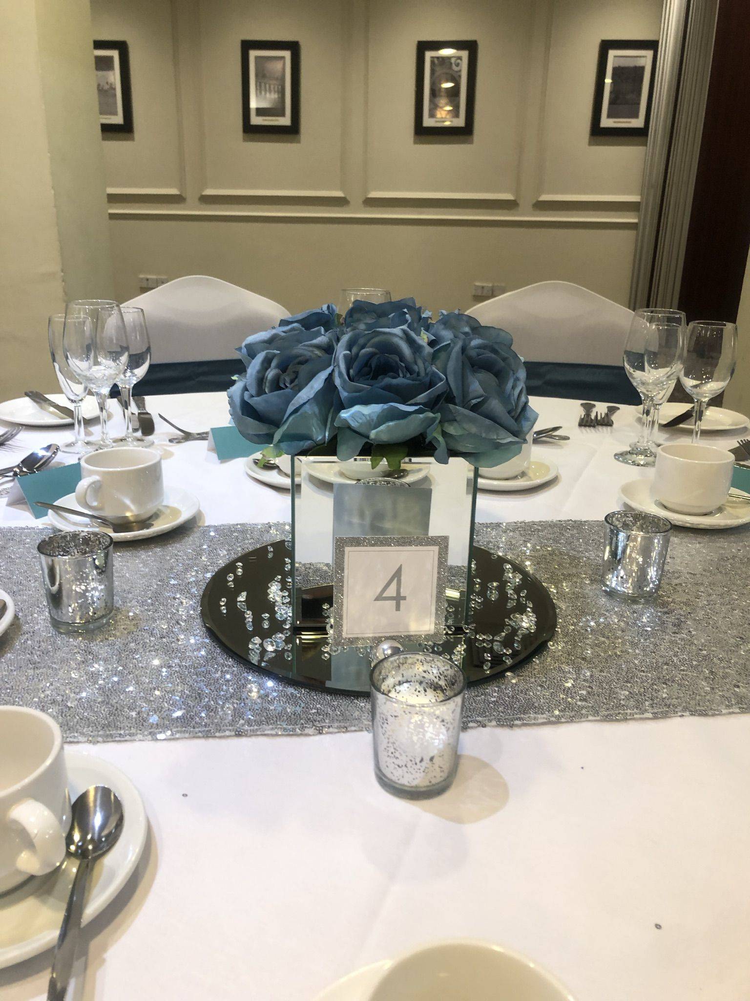 a table is set with silver and white plates and silverware.